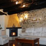 Salón con chimenea y pared de piedra del Hotel Villa Fontanas, Hontanas